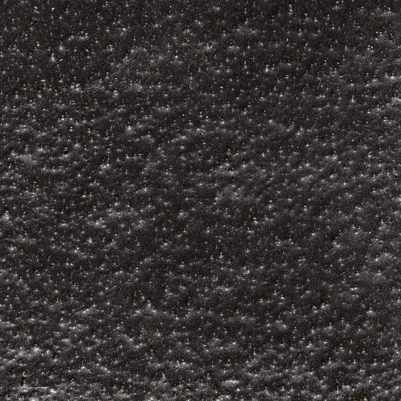 Close-up of a dark, textured surface with small white specks scattered throughout.
